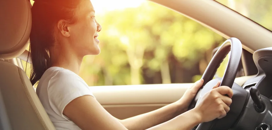 Student driver smiling behind the wheel on a sunny day